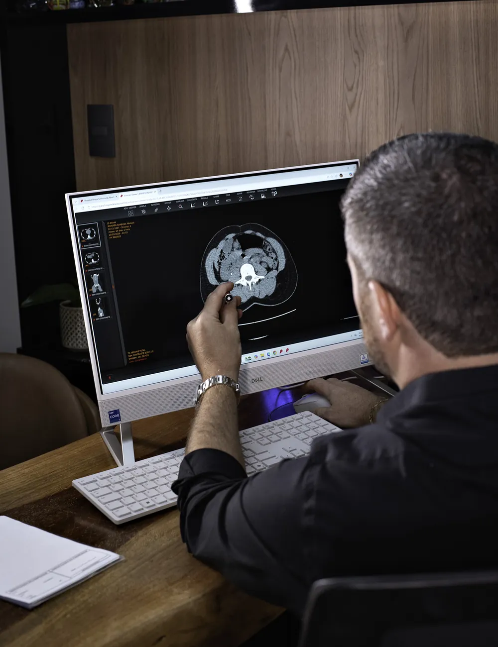 Dr. Thales analisando uma tomografia no monitor do consultório